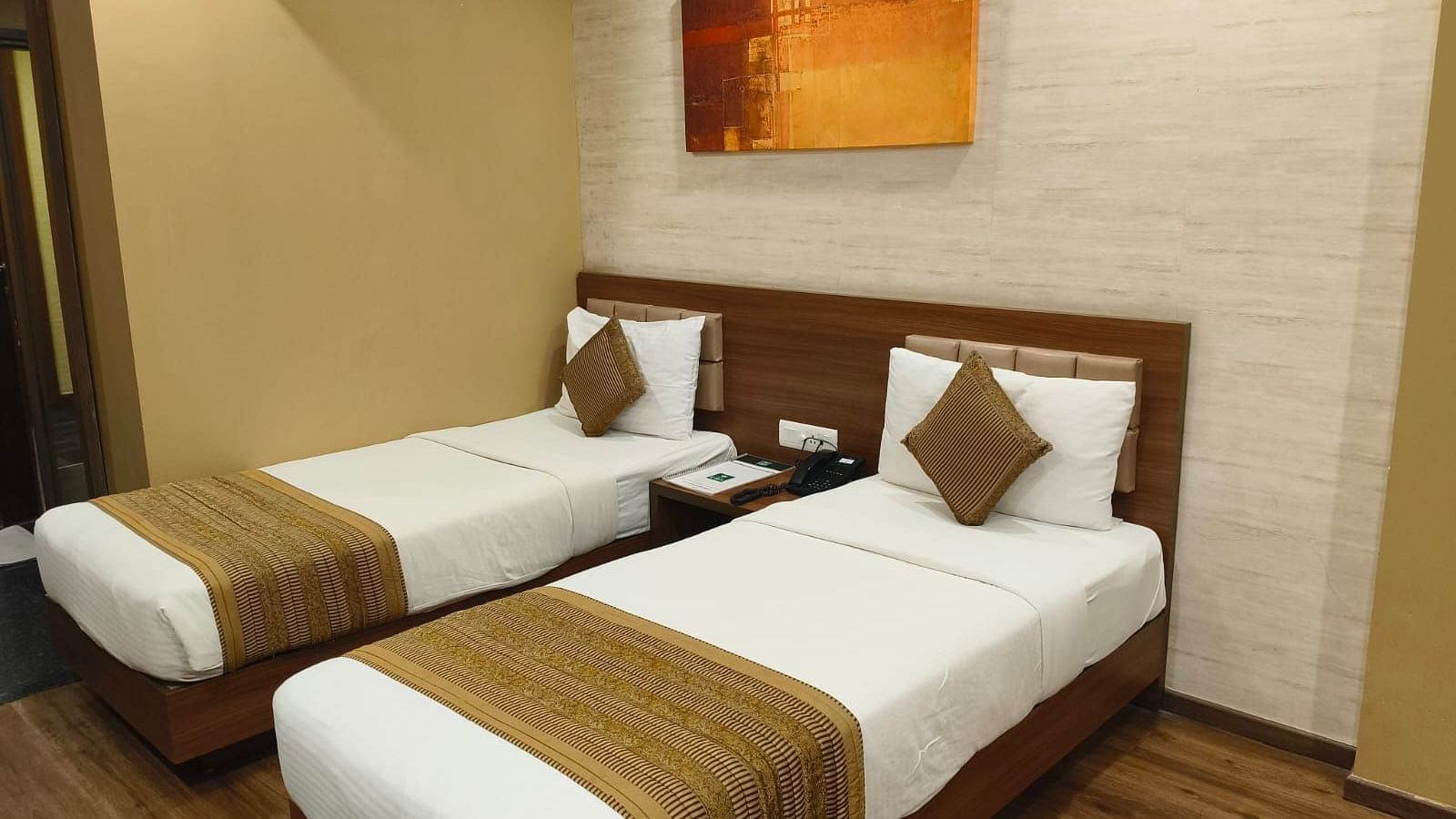 A side corner angle view of the room with twin beds, a wall frame, and an AC at Le ROI Digha Hotel, West Bengal.